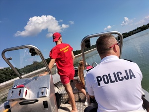 Zdjęcie przedstawia: policjanta i ratowników podczas patrolu na łódce.