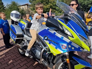 Zdjęcie przedstawia: dziecko siedzące na policyjnym motocyklu.
